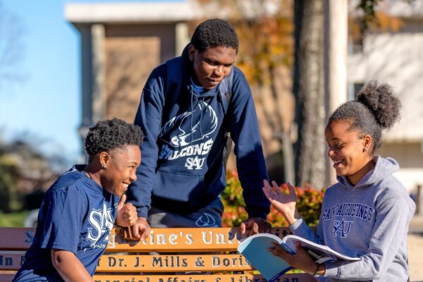 SAU students students sitting on a bench with a book